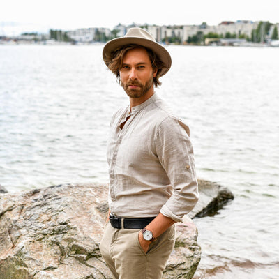 Men wearing hat standing on the rock next to ocean