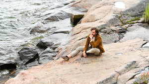 Men sitting on the rock watching ocean wearing adventurister gold